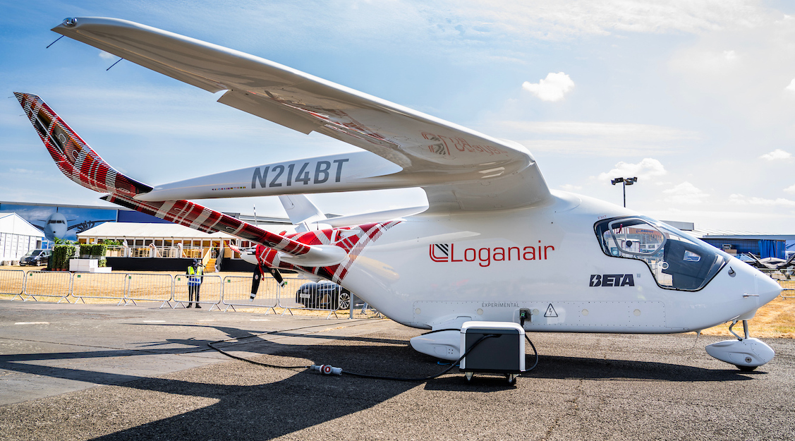 BETA’s Alia CX300 all-electric aircraft shown charging. The aircraft is decorated with the signature Loganair logo and tartan print, also featuring the BETA Technologies and Royal Mail logos.