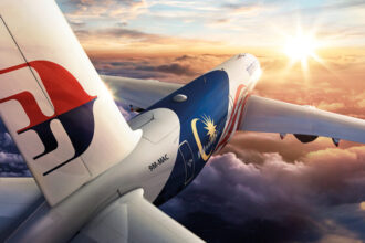 An aircraft flying into a golden sunset, with fluffy clouds below.