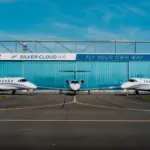 Silver Cloud Air building in the background with three aircraft in view; one in the centre and one either side of it. Blue sky in the background.