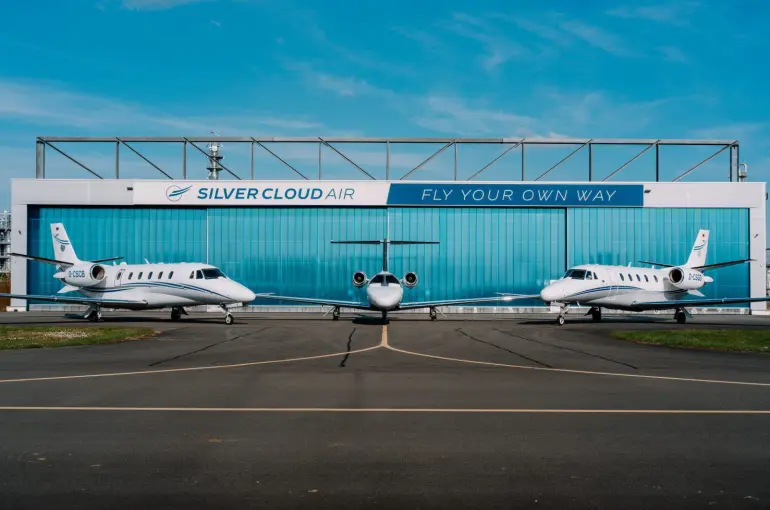 Silver Cloud Air building in the background with three aircraft in view; one in the centre and one either side of it. Blue sky in the background.