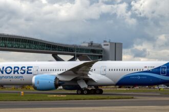 Norse Atlantic Boeing 787-9 Dreamliner registration G-CKOF, named 'Redwood,' taxiing past a terminal jet bridge at London Gatwick Airport.