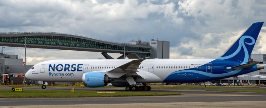 Norse Atlantic Boeing 787-9 Dreamliner registration G-CKOF, named 'Redwood,' taxiing past a terminal jet bridge at London Gatwick Airport.