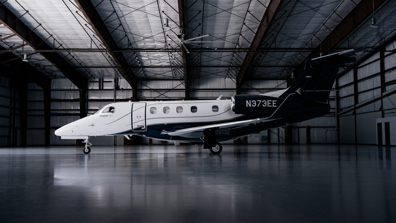 Embraer Phenom 300EV light jet parked inside a hangar, registration N373EE visible on the tail.