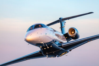 Embraer Phenom 300EV in flight at sunset, close-up view of the nose, cockpit and right engine.