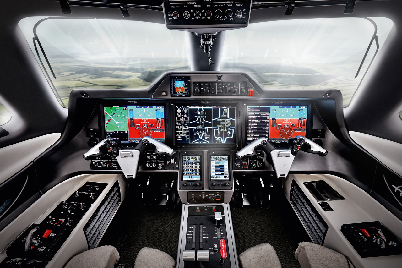 Phenom 300EV cockpit showing the Prodigy Touch flight deck with multiple Garmin G3000 displays and dual control yokes.
