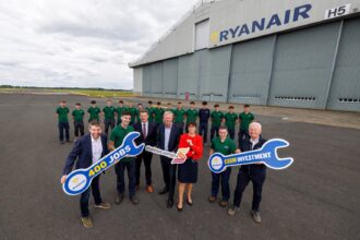 Ryanair and Shannon Airport Group Posing with signs shaped like spanners outside the existing Ryanair hangar at Shannon Airport.