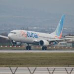 A Flydubai Boeing 737 plane landing on tarmac surrounded by green grass.