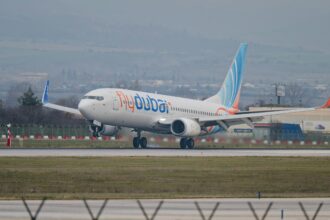 A Flydubai Boeing 737 plane landing on tarmac surrounded by green grass.