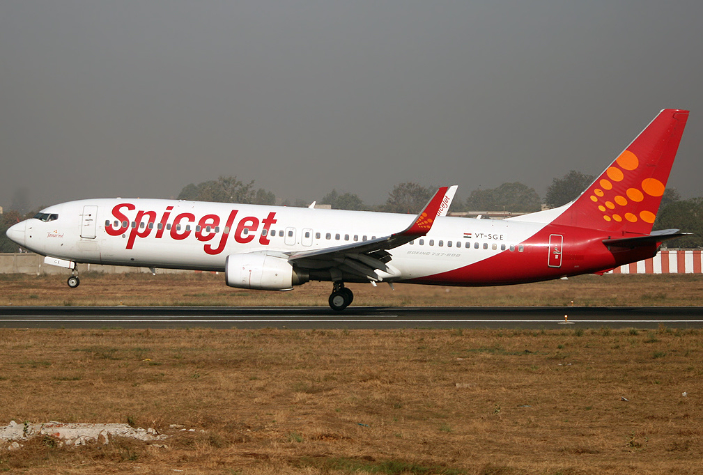 A side view of a Spicejet Boeing 737-800 preparing to take off, the front wheel is off the tarmac and the plane is tilted forward.