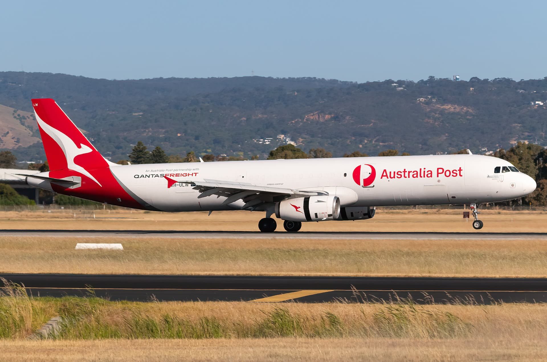 Image shows a Qantas Freight Airbus A321P2F aircraft grounded at Adelaide International Airport during the day