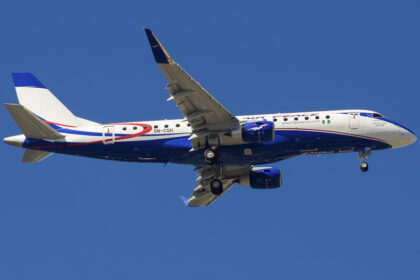 An Air Peace plane mid-flight, showing the bottom of the plane's fuselage and underside of its wings.