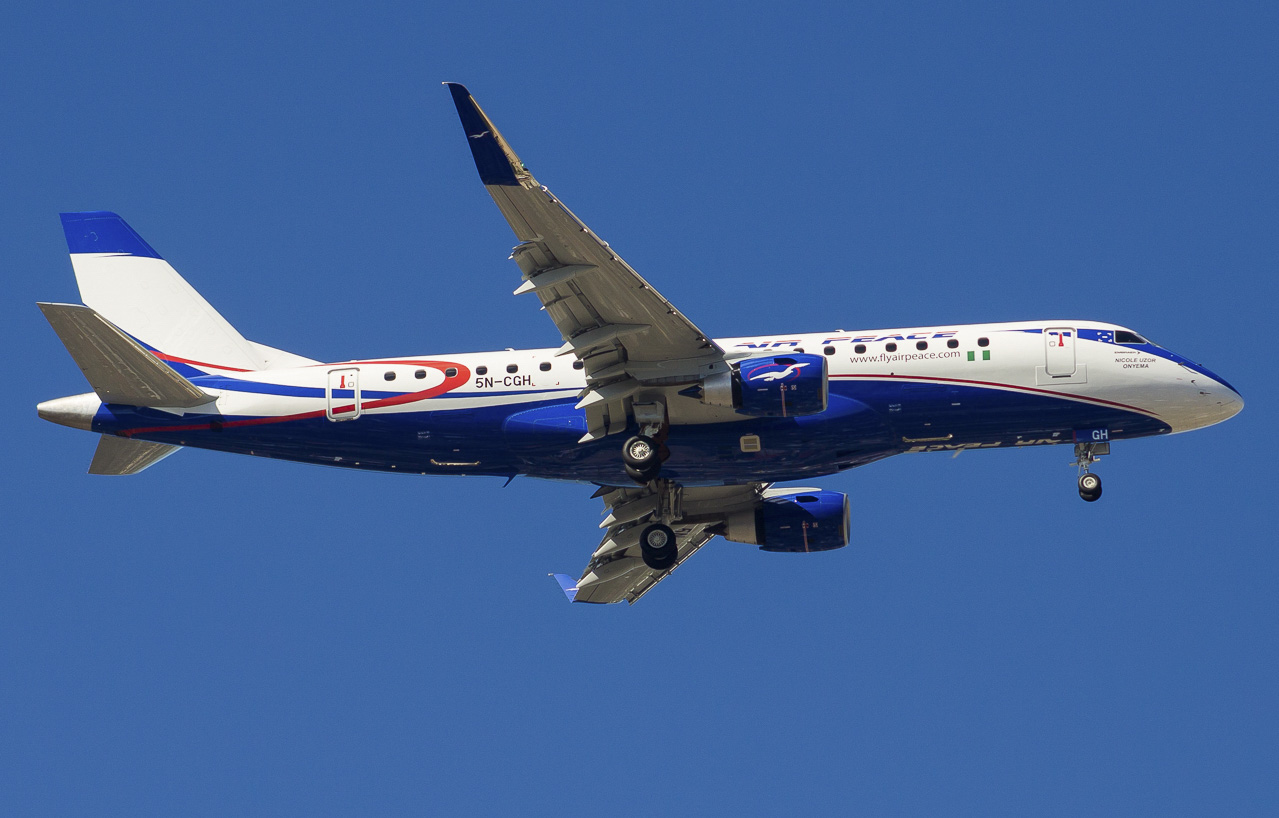An Air Peace plane mid-flight, showing the bottom of the plane's fuselage and underside of its wings.