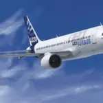 Airbus A320-neo flying through the clouds front side view. Branded with Airbus logos and colourways with a blue sky and clouds background.