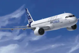 Airbus A320-neo flying through the clouds front side view. Branded with Airbus logos and colourways with a blue sky and clouds background.