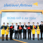 Members of Vietravel Airlines at the opening of its booth at the National Achievements Exhibition, with some holding a small Vietnamese flag.