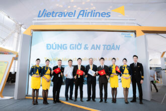 Members of Vietravel Airlines at the opening of its booth at the National Achievements Exhibition, with some holding a small Vietnamese flag.