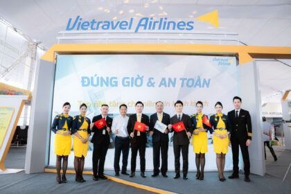 Members of Vietravel Airlines at the opening of its booth at the National Achievements Exhibition, with some holding a small Vietnamese flag.
