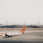 A Jejuair Boeing 737-800 parked at the Gimpo International Airport tarmac with a cloudy sky backdrop and hills in the horizon