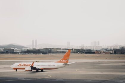 A Jejuair Boeing 737-800 parked at the Gimpo International Airport tarmac with a cloudy sky backdrop and hills in the horizon