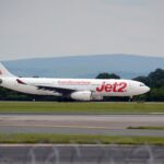 Jet2 aircraft landing on runway with a clear sky and mountains in the background.