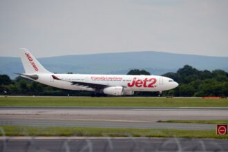 Jet2 aircraft landing on runway with a clear sky and mountains in the background.