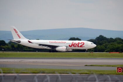 Jet2 aircraft landing on runway with a clear sky and mountains in the background.