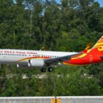 A Hainan Airlines Boeing 737 aircraft preparing to land on tarmac with trees in the background.