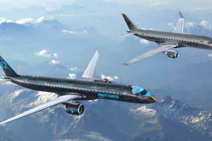 two black Embraer aircraft flying side by side above the clouds
