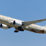 An Etihad Airways B787 mid-flight with a blue sky in the background.