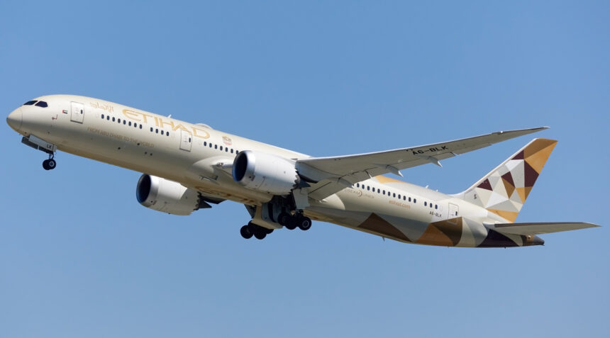 An Etihad Airways B787 mid-flight with a blue sky in the background.