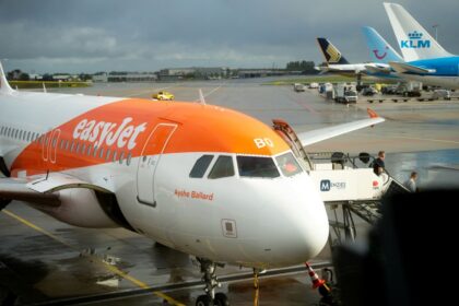A front view of an easyJet aircraft waiting on tarmac with another airplane in the background.