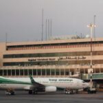 An Iraqi Airways jet on the apron at Baghdad International Airport with airport buildings visible in the background