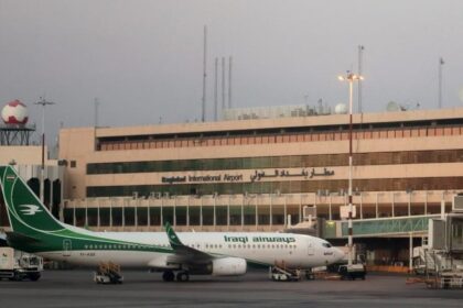 An Iraqi Airways jet on the apron at Baghdad International Airport with airport buildings visible in the background