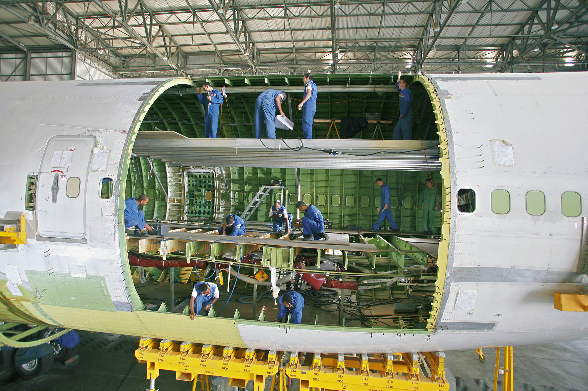 Technicians working inside the fuselage of an aircraft undergoing passenger-to-freighter conversion, with structural framing exposed.