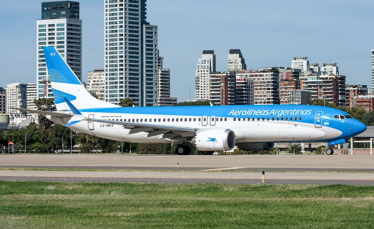 Aerolíneas Argentinas Boeing 737-8 MAX aircraft, registration LV-HKV, on the tarmac with city skyline in the background.