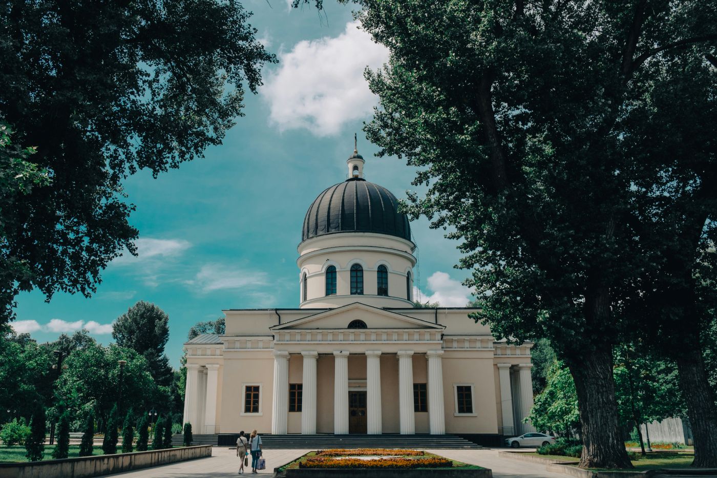 A front view of Moldova's The Metropolitan Cathedral with backdrop of a clear sky backdrop and trees on the side.