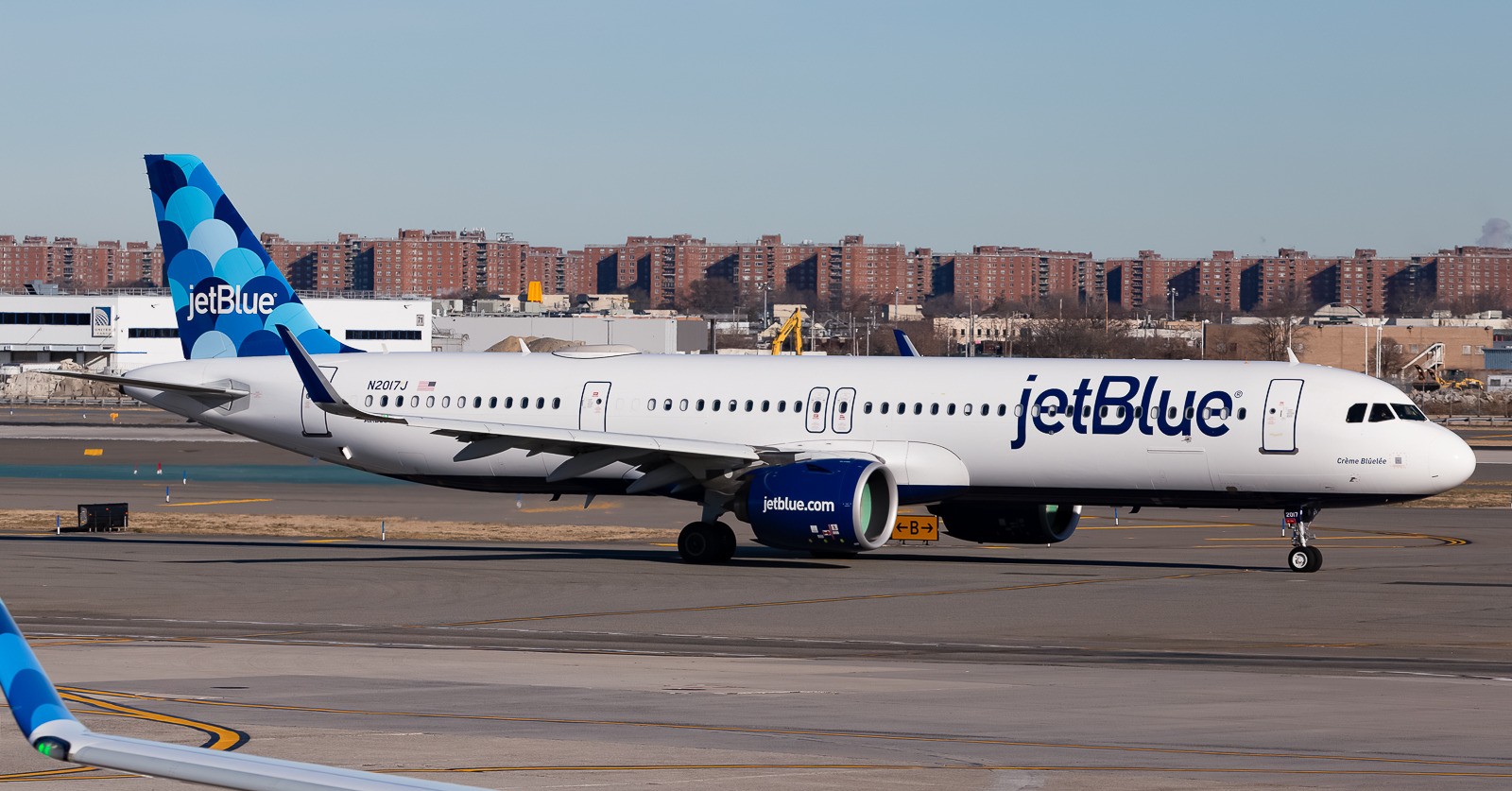 JetBlue Airbus A321-271NX registered N2017J taxiing on the tarmac with airport buildings in the background