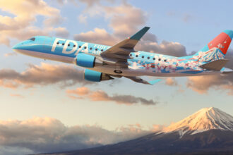 An image of an FDA aircraft flying with a snowy mountain top and clouds in the background.