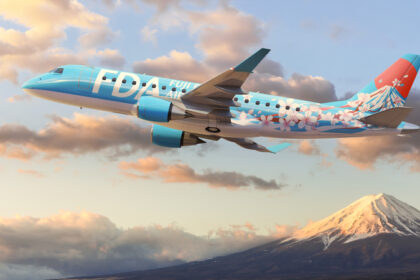 An image of an FDA aircraft flying with a snowy mountain top and clouds in the background.