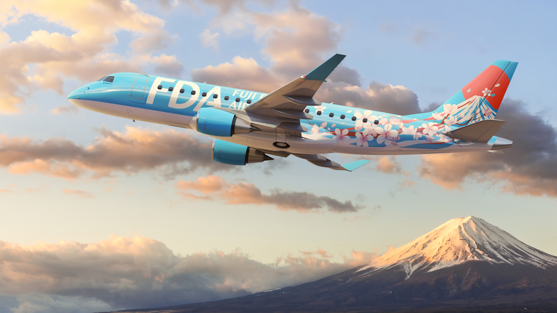 An image of an FDA aircraft flying with a snowy mountain top and clouds in the background.