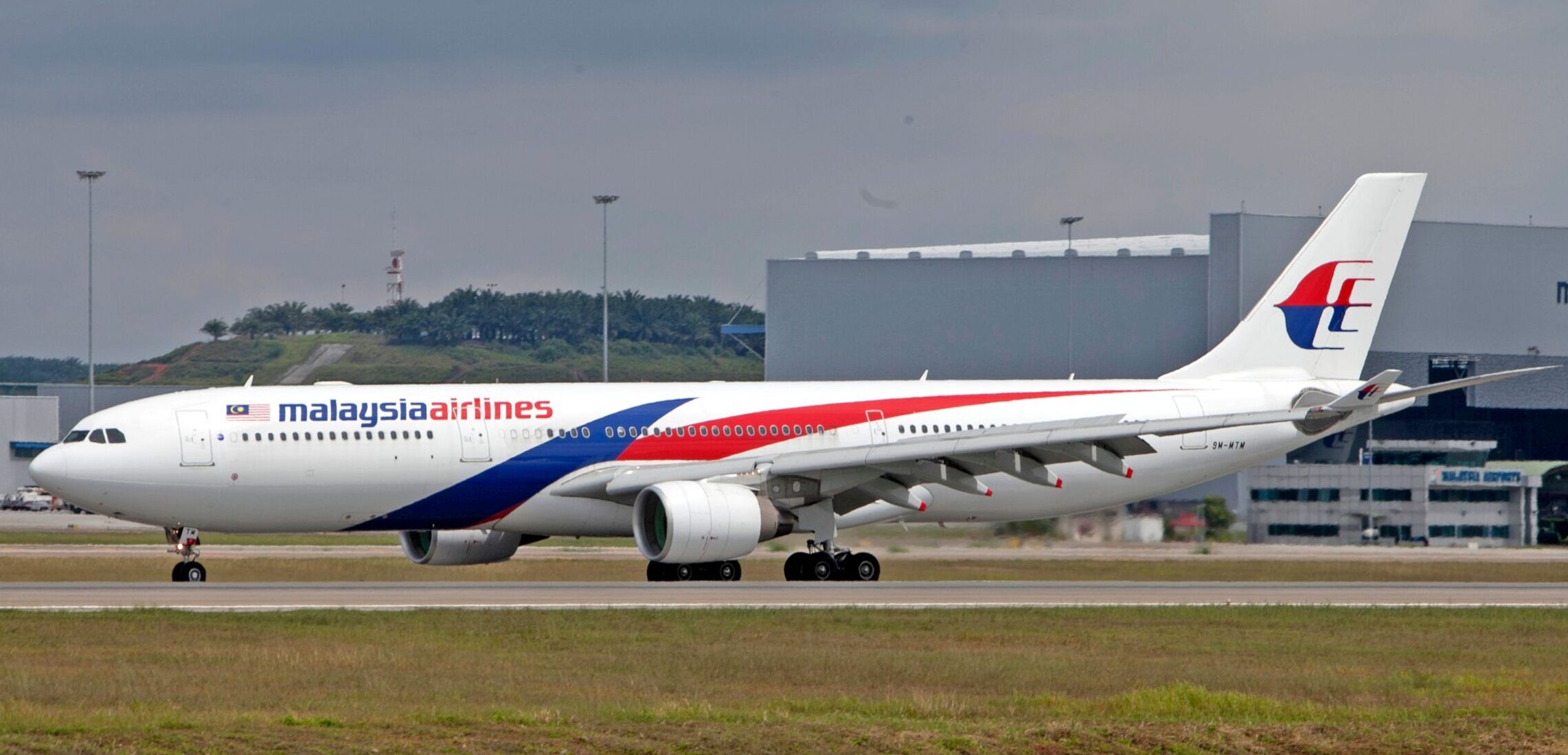 Malaysian Airlines plane on runway with airport in background
