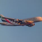 An Emirates Airbus A380 flying against a clear blue sky, with the airline’s logo and distinctive UAE flag colours visible on the aircraft