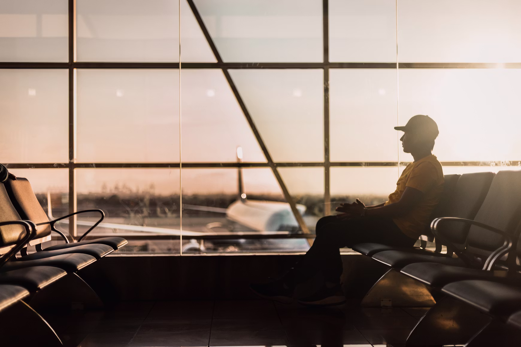 Solo traveler waiting at the airport window representing the logistics of multi-state long-stay travel planning. 