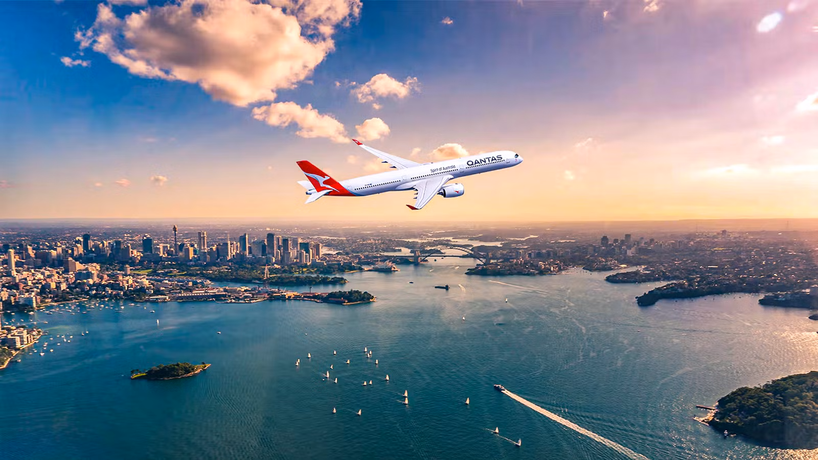 Qantas aircraft flying over Sydney harbour with landmarks like the Opera House and Harbour Bridge in the background at sunrise