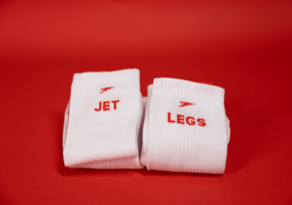 Image shows two pairs of white socks with 'jet' and 'legs' writing in red on each with red plane pictures above on a red background