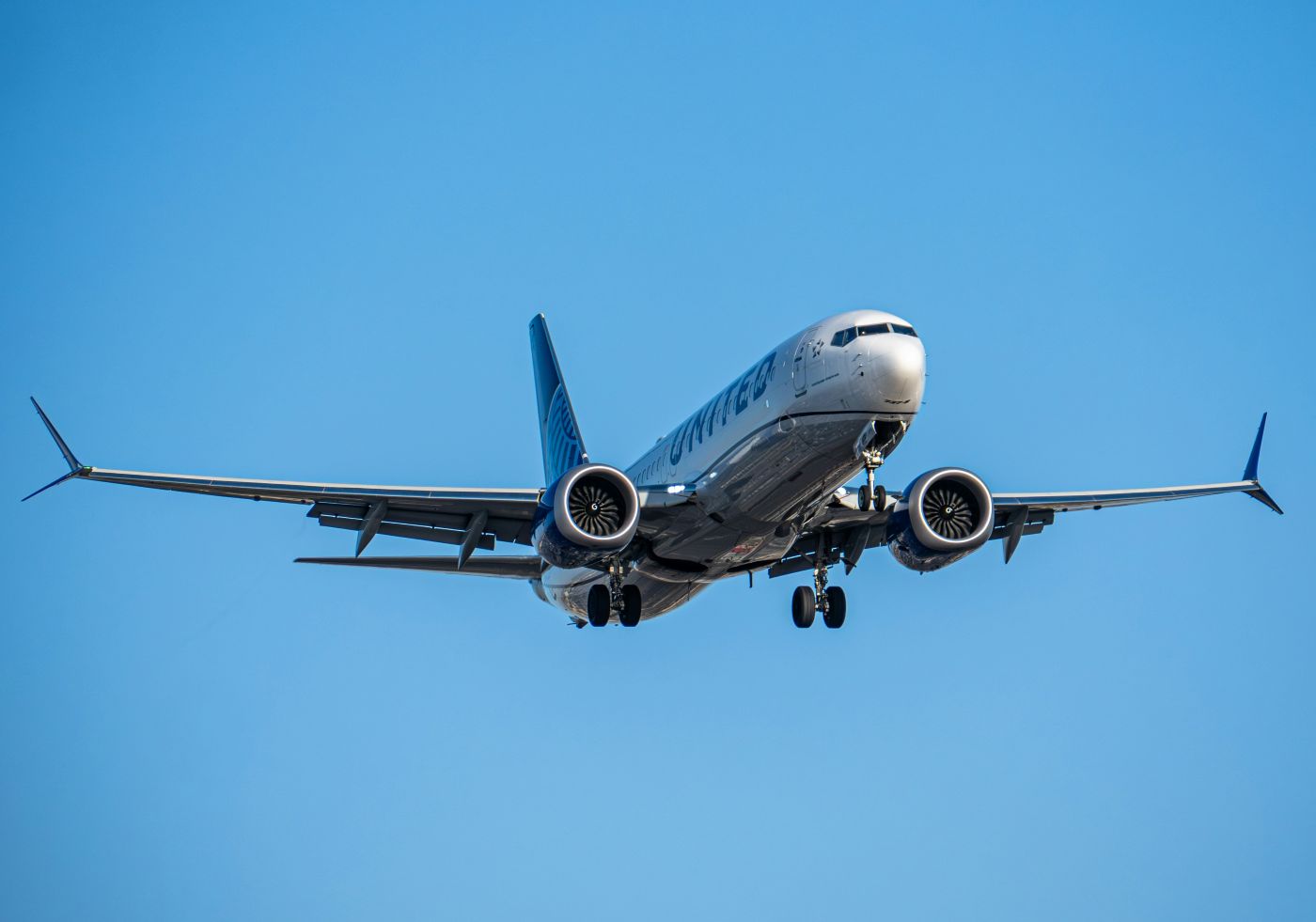 A front view of a Boeing 737-9 mid-flight in a clear blue sky