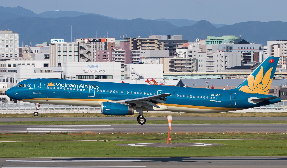 Vietnam Airlines Airbus A321, registration VN-A602, touching down with a city skyline in the background.
