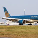 Vietnam Airlines Airbus A350 taxiing on the runway with airport buildings in the background.