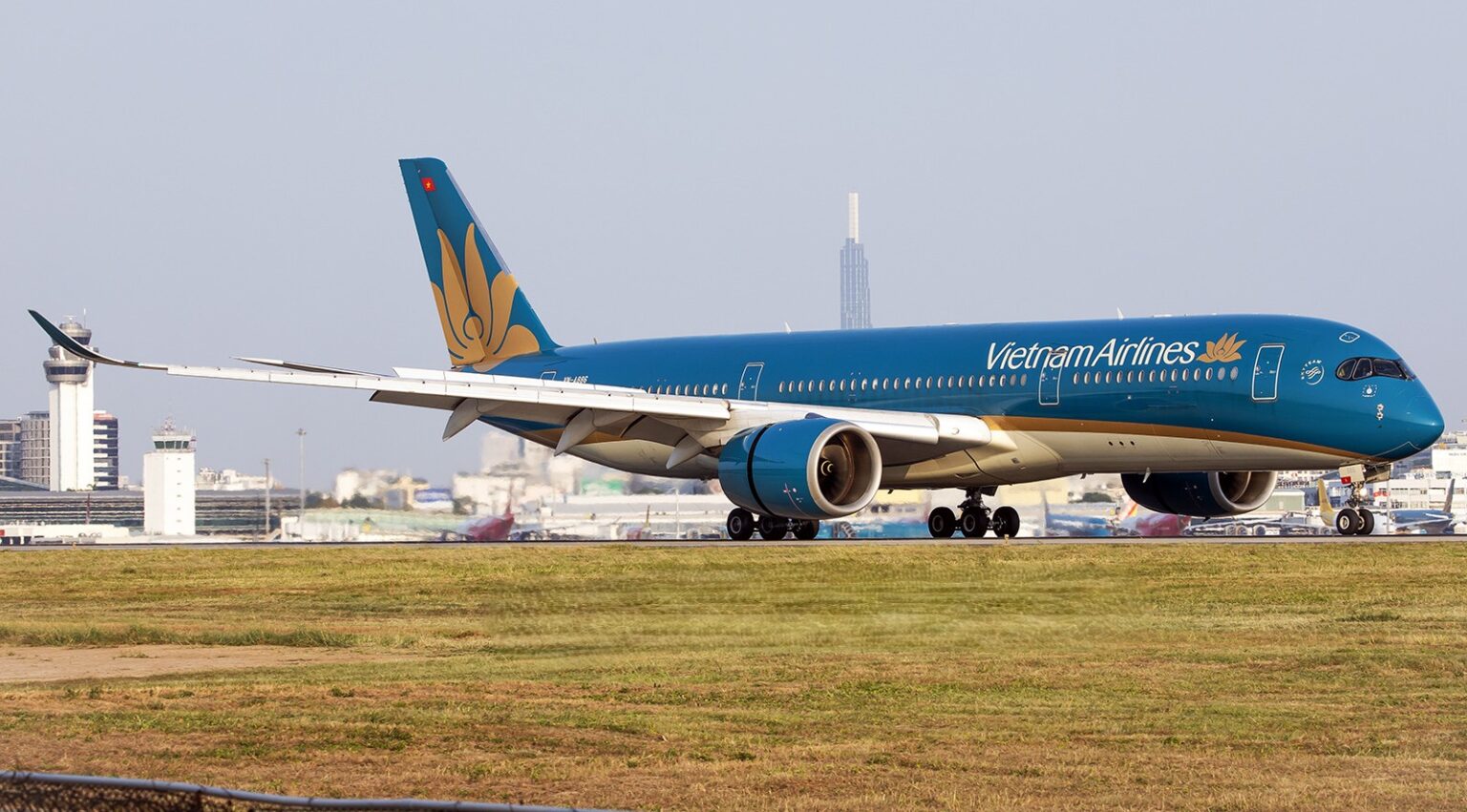 Vietnam Airlines Airbus A350 taxiing on the runway with airport buildings in the background.