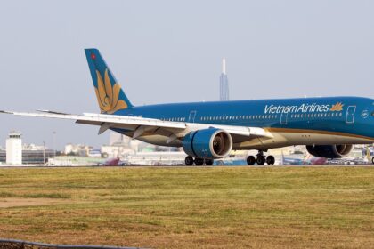 Vietnam Airlines Airbus A350 taxiing on the runway with airport buildings in the background.